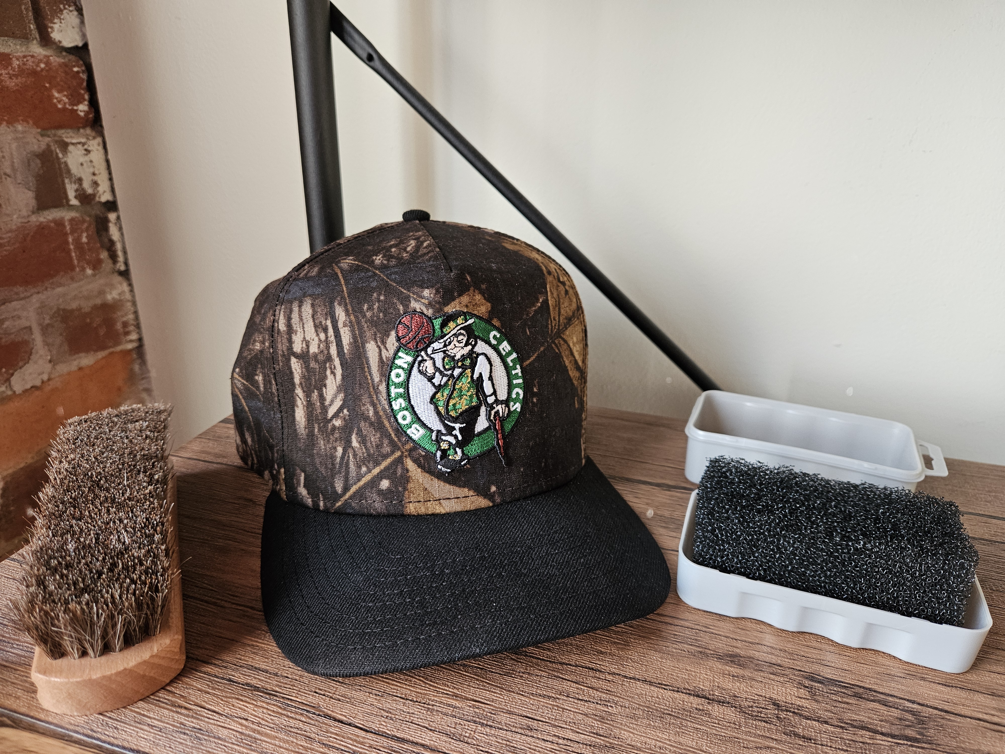 Boston Celtics fitted hat with cap brush and horsehair brush on a wood surface